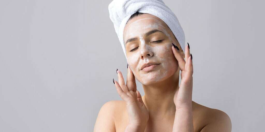 Beauty portrait of woman in white towel on head with a sponge for a body in view of a pink heart. Skincare cleansing eco organic cosmetic spa relax concept.