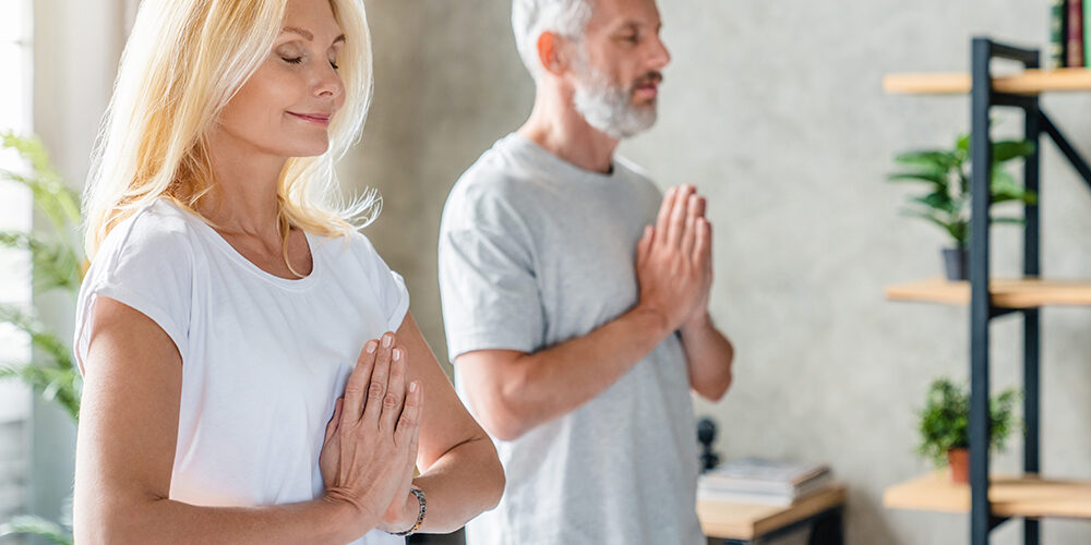 Close up of middle aged couple doing yoga and fitness training at home