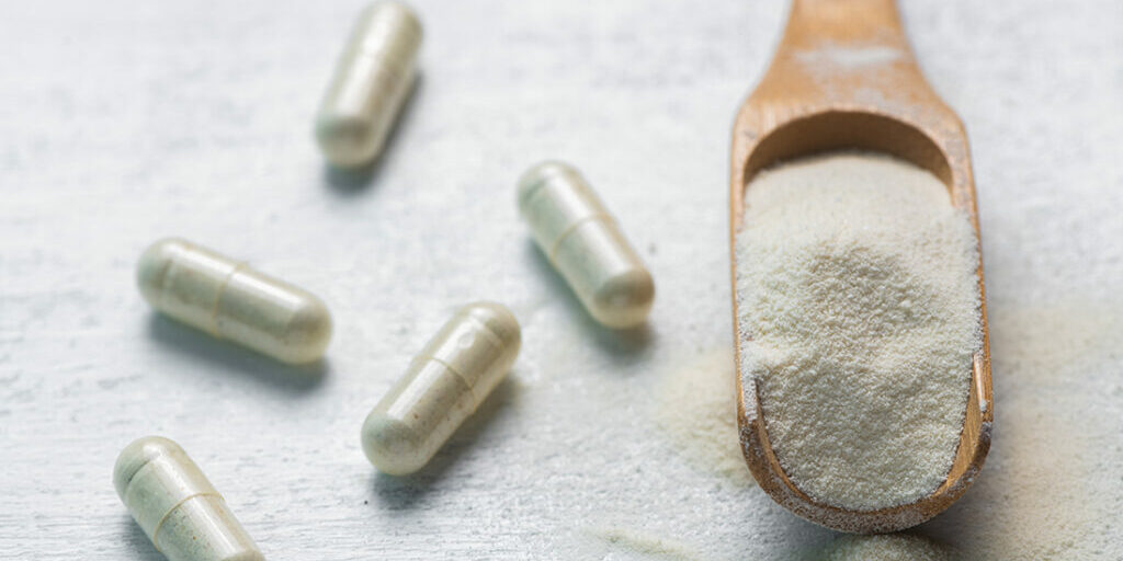 collagen in tablets and powder on wooden white background. Natural beauty and health supplement. Flat lay, top view