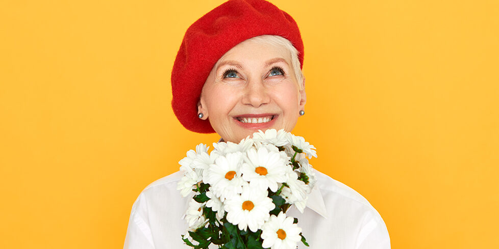 Spring time, freshness and nature concept. Attractive happy middle aged woman having dreamy excited expression, holding bunch of field flowers she picked in countryside, inhaling floral aroma